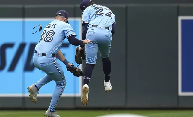 Toronto Blue Jays right fielder Nathan Lukes (38) and second baseman Ernie Clement (22) collide while trying to field a single hit by Minnesota Twins' Royce Lewis (23) during the sixth inning of a baseball game Sunday, June 8, 2025, in Minneapolis. (AP Photo/Abbie Parr)