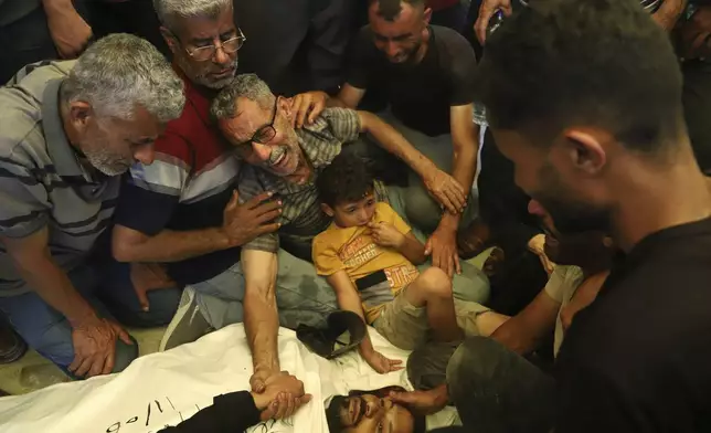 Ata Qasas, center, mourns over the body of his son Rashad Qasas, who was killed while heading to an aid distribution hub, during his funeral in Rafah, southern Gaza Strip, Wednesday, June 11, 2025. (AP Photo/Mariam Dagga)