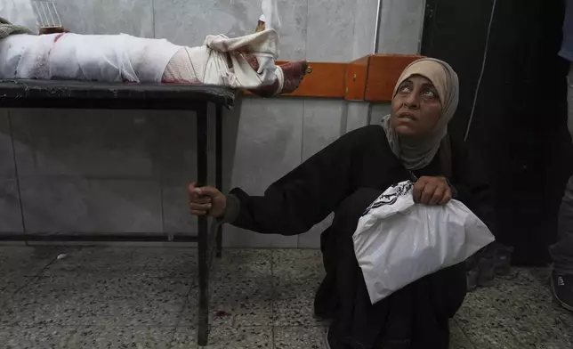 A Palestinian woman waits next to her son, who was injured last night while trying to get access to humanitarian aid, at the al-Shifa Hospital, in Gaza City, Wednesday, June 11, 2025. (AP Photo/Jehad Alshrafi)