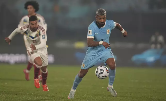 Uruguay's Rodrigo Aguirre carries the ball as Venezuela's Alexander Gonzalez follows during a qualifying soccer match for the FIFA World Cup 2026 at Centenario Stadium in Montevideo, Uruguay, Tuesday, June 10, 2025. (AP Photo/Matilde Campodonico)