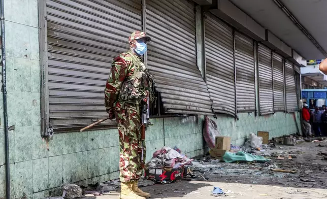 A police officer stands guard at a vandalized shop following the one-year anniversary of deadly anti-tax demonstrations in Nairobi, Kenya, Thursday, June 26, 2025. (AP Photo/Patrick Ngugi)