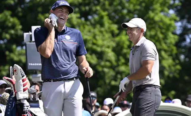 Keegan Bradley, left, shares a light moment with Rory McIlroy, of Northern Ireland, right, as they start the first round of the Travelers Championship golf tournament at TPC River Highlands, Thursday, June 19, 2025, in Cromwell, Conn. (AP Photo/Jessica Hill)