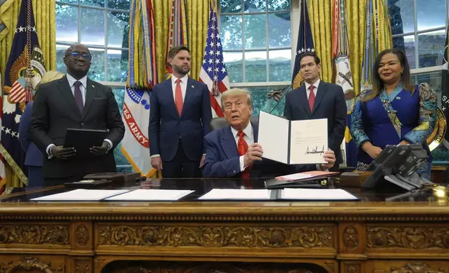 President Donald Trump holds up a signed document to present to Congo's Foreign Minister Therese Kayikwamba Wagner, right, as Rwanda's Foreign Minister Olivier Nduhungirehe, from left, Vice President JD Vance and Secretary of State Marco Rubio watch, Friday, June 27, 2025, in the Oval Office at the White House in Washington. (AP Photo/Manuel Balce Ceneta)