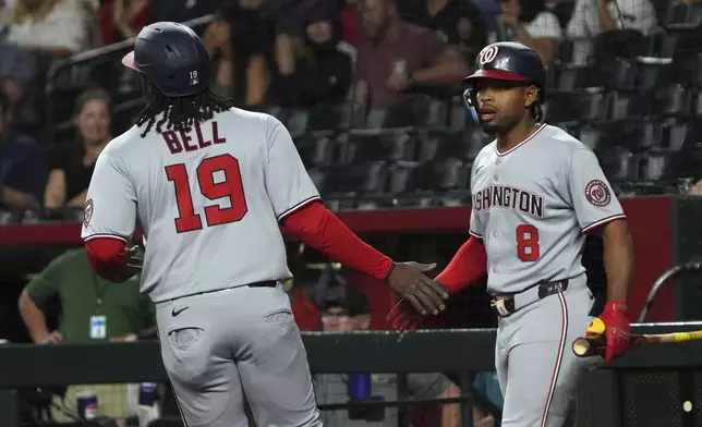 Washington Nationals' Josh Bell (19) celebrates with José Tena (8) after scoring a run against the Arizona Diamondbacks on a double hit by Keibert Ruiz in the first inning during a baseball game, Saturday, May 31, 2025, in Phoenix. (AP Photo/Rick Scuteri)