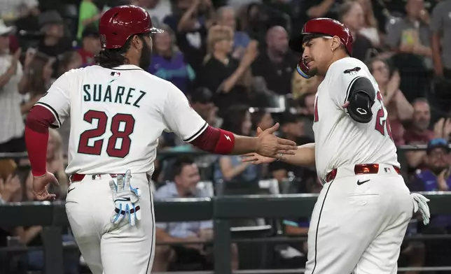 Arizona Diamondbacks' Eugenio Suárez (28) and Josh Naylor celebrate after scoring runs against the Washington Nationals on a triple hit by Pavin Smith in the sixth inning during a baseball game, Saturday, May 31, 2025, in Phoenix. (AP Photo/Rick Scuteri)