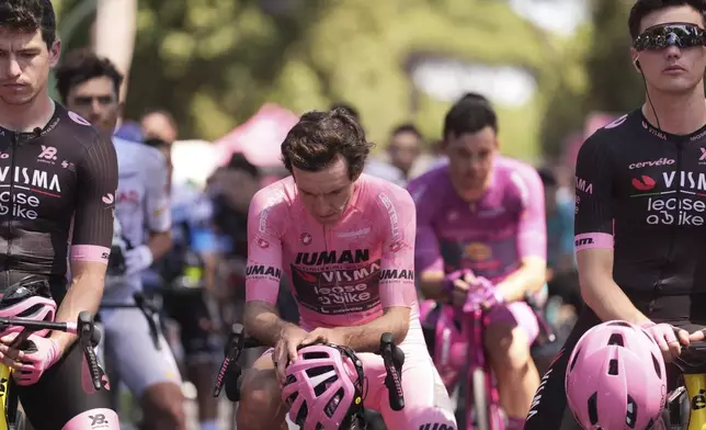 Britain's Simon Yates, in the pink jersey, center, observes a minute of silence with other riders for the passing of former Dutch cyclist Robert Gesink's wife, during the last stage of the Giro d'Italia cycling race, in Rome, Sunday, June 1, 2025. (Fabio Ferrari/LaPresse via AP)