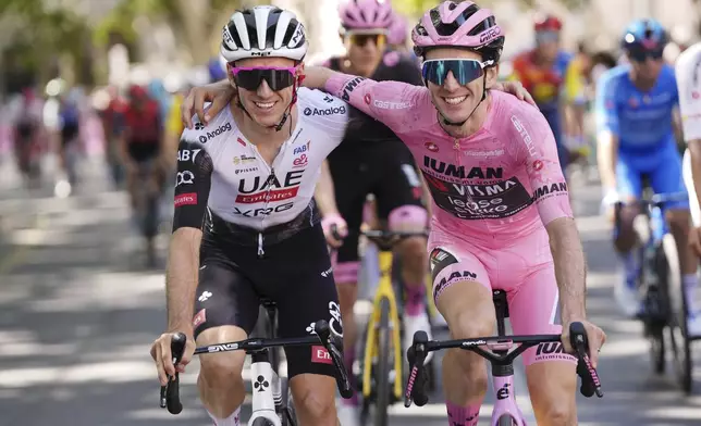 Britain's Simon Yates, in the pink jersey, shares a light moment with his brother Adam Yates, during the last stage of the Giro d'Italia cycling race, in Rome, Sunday, June 1, 2025. (Fabio Ferrari/LaPresse via AP)