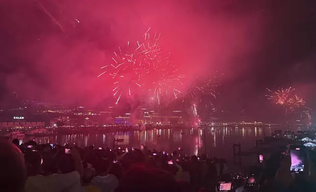 People watch fireworks explode above the Douro river celebrating the Saint John feast in Porto, northern Portugal, in the first minutes of Tuesday, June 24, 2025. (AP Photo/Helena Alves)