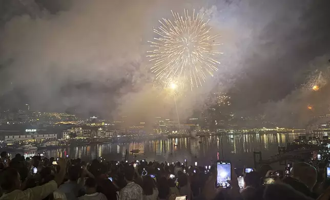 People watch fireworks explode above the Douro river celebrating the Saint John feast in Porto, northern Portugal, in the first minutes of Tuesday, June 24, 2025. (AP Photo/Helena Alves)
