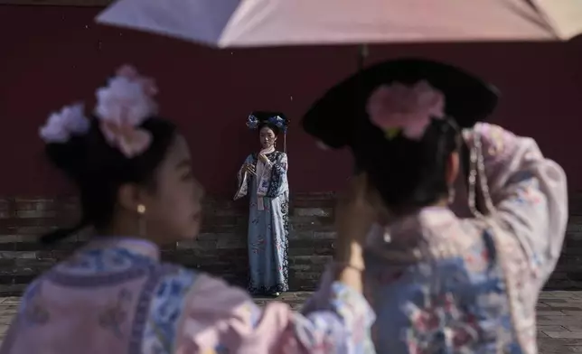 A woman dressed in Qing Dynasty attire poses for souvenir photograph as they visit the Temple of Heaven during the weekend holiday, in Beijing, Sunday, June 15, 2025. (AP Photo/Andy Wong)