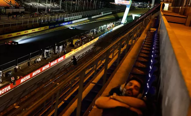 A fan sleeps in the stands during the 24-hour Le Mans endurance race, Sunday, June 15, 2025 in Le Mans, western France. (AP Photo/Jeremias Gonzalez)