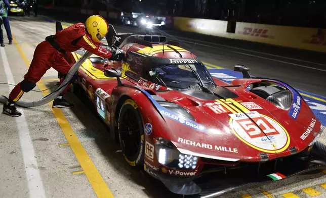 Pit crew members work on the No.51 a Ferrari 499P with Alessandro Pier Guidi of Italy, James Calado of Great Britain and Antonio Giovinazzi of Italy, races during the 24-hour Le Mans endurance race, Sunday, June 15, 2025 in Le Mans, western France. (AP Photo/Jeremias Gonzalez)