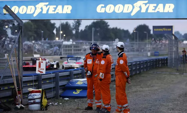 Marshals watch the cars on the race track during the 24-hour Le Mans endurance race, Saturday June 14, 2025 in Le Mans, western France. (AP Photo/Jeremias Gonzalez)