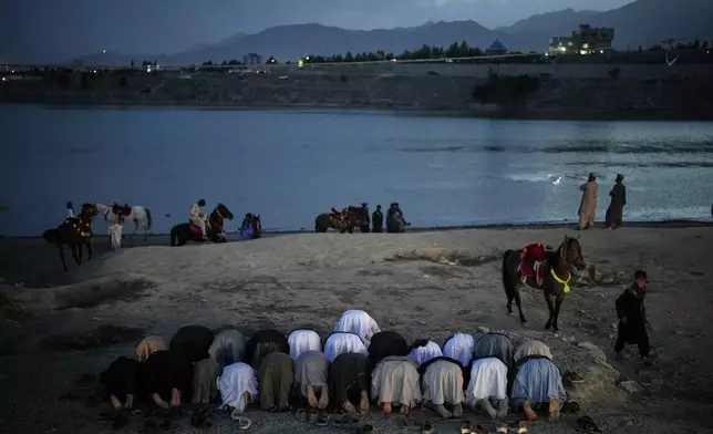 Afghan men pray by the lake Qargha in Kabul, Afghanistan, Monday, June 9, 2025. (AP Photo/Ebrahim Noroozi)