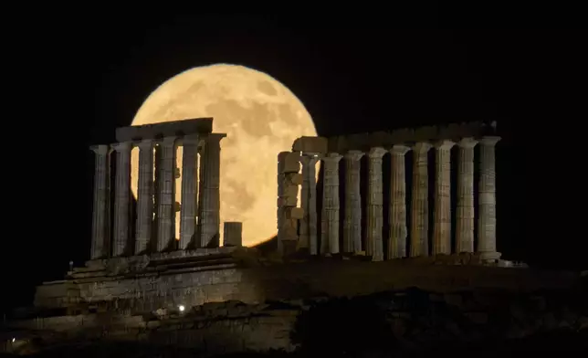 The strawberry Moon rises in the sky behind the ancient temple of Poseidon at Cape Sounion, about 70 kilometers (45 miles) south of Athens, Greece, Wednesday, June 11, 2025. (AP Photo/Petros Giannakouris)