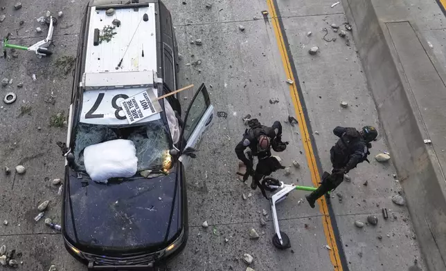 Two California Highway Patrol officers try to dodge rocks being thrown near the Metropolitan Detention Center in downtown Los Angeles, Sunday, June 8, 2025, following last night's immigration raid protest. (AP Photo/Jae C. Hong)