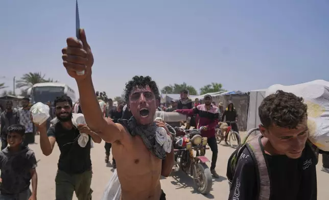 A Palestinian shouts to the camera in Arabic "We get food with the taste of death and blood" as he carries a bag containing food and humanitarian aid packages delivered by the Gaza Humanitarian Foundation, a U.S.-backed organization, in Rafah, southern Gaza Strip, Tuesday, June 10, 2025. (AP Photo/Abdel Kareem Hana)