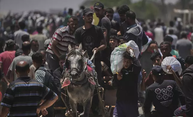 Palestinians carry bags containing food and humanitarian aid packages delivered by the Gaza Humanitarian Foundation, a U.S.-backed organization, in Rafah, southern Gaza Strip, Monday, June 9, 2025. (AP Photo/Abdel Kareem Hana)