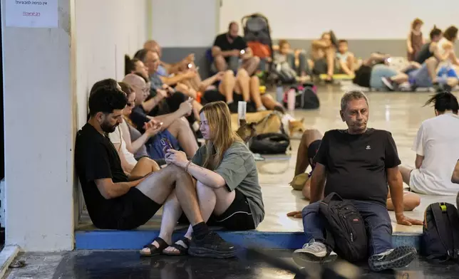 Israelis sit in a shelter during sirens warning of incoming fire in Tel Aviv, early Sunday, June 15, 2025. (AP Photo/Baz Ratner)