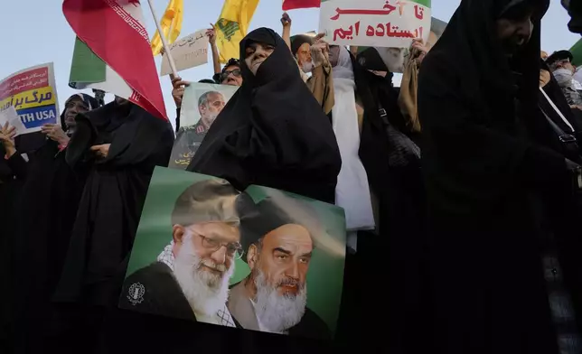 An Iranian woman holds a poster of the late revolutionary founder Ayatollah Khomeini, right, and Supreme Leader Ayatollah Ali Khamenei in an anti-U.S. and anti-Israeli rally at Enqelab-e-Eslami (Islamic Revolution) square in downtown Tehran, Iran, Tuesday, June 24, 2025. (AP Photo/Vahid Salemi)
