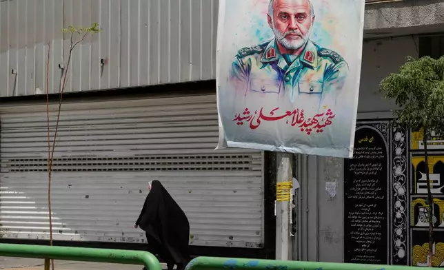 An Iranian woman walks past a banner showing head of the paramilitary Revolutionary Guard's Khatam al-Anbiya Central Headquarters Gen. Gholam Ali Rashid, who was killed in Israeli strike, at Enqelab-e-Eslami (Islamic Revolution) street in downtown Tehran, Iran, Tuesday, June 24, 2025. (AP Photo/Vahid Salemi)