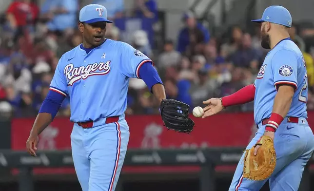 Texas Rangers first base Jake Burger (21) hands the baseball game ball to starting pitcher Kumar Rocker during the fifth inning against the Chicago White Sox, Sunday, June 15, 2025, in Arlington, Texas. (AP Photo/LM Otero)