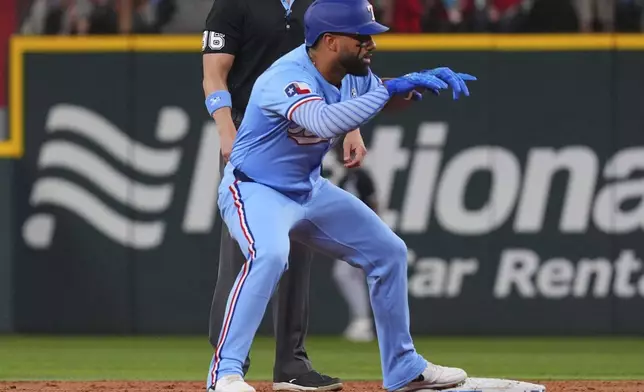 Texas Rangers' Ezequiel Duran, front, stands on second base and reacts after hitting a double that scored teammate Adolis García during the second inning of a baseball game against the Chicago White Sox, Sunday, June 15, 2025, in Arlington, Texas. (AP Photo/LM Otero)