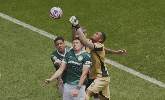 Botafogo's goalkeeper John clears the ball away from Palmeiras' Bruno Fuchs, center, and Vitor Roque during the Club World Cup round of 16 soccer match between Palmeiras and Botafogo in Philadelphia, Saturday, June 28, 2025. (AP Photo/Chris Szagola)