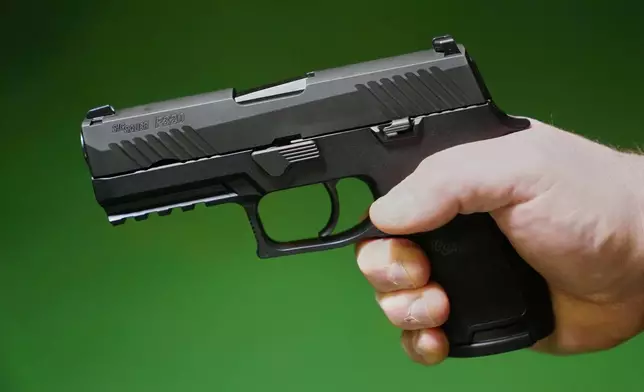 A Sig Sauer P320 handgun is held by a Maine gun shop owner, Tuesday, June 17, 2025. (AP Photo/Robert F. Bukaty)