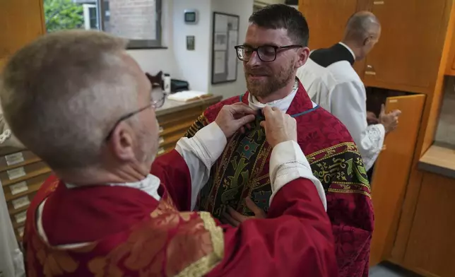 The Rev. Donald J. Planty, Jr., left, assists the Rev. Tim Banach with a microphone before Banach's first Mass at St. Charles Borromeo Catholic Church in Arlington, Va., on Sunday, June 8, 2025. (AP Photo/Jessie Wardarski)