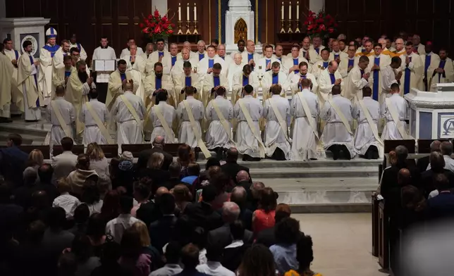 Priests and bishops bless the 12 newly ordained priests during Mass at the Cathedral of Saint Thomas More in Arlington, Va., on Saturday, June 7, 2025. (AP Photo/Jessie Wardarski)