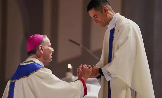 The Rev. Alfredo Tuesta gives his first blessing as a newly ordained priest to Bishop Michael Burbidge, who leads the Diocese of Arlington, at the Cathedral of Saint Thomas More in Arlington, Va., on Saturday, June 7, 2025. (AP Photo/Jessie Wardarski)