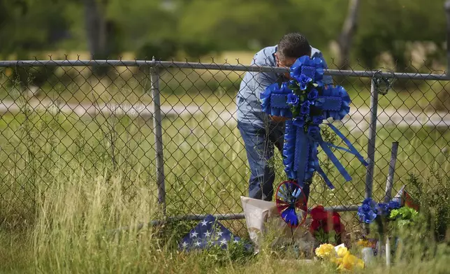 Adriane Reyes adds a cross to candles, flowers, and notes that create a make-shift memorial for voice actor Jonathan Joss who was recently killed, Tuesday, June 3, 2025, in San Antonio. (AP Photo/Eric Gay)