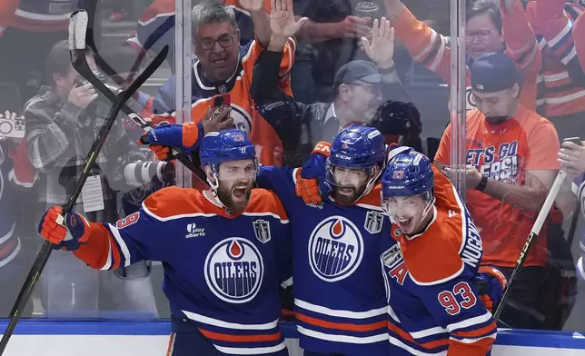 Edmonton Oilers' Leon Draisaitl, from left to right, Evan Bouchard, and Ryan Nugent-Hopkins celebrate Draisaitl's winning goal during the first overtime period in Game 1 of the NHL Stanley Cup Final against the Florida Panthers, in Edmonton, Alberta, on Wednesday, June 4, 2025. (Darryl Dyck/The Canadian Press via AP)
