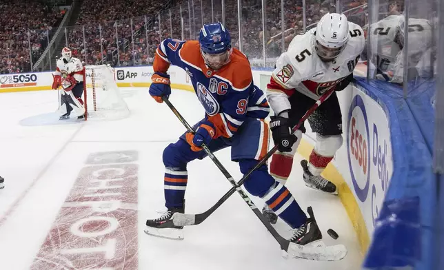 Florida Panthers' Aaron Ekblad (5) and Edmonton Oilers' Connor McDavid (97) battle for the puck during the first overtime period in Game 1 of the NHL hockey Stanley Cup final series in Edmonton, Alberta, Wednesday, June 4, 2025. (Jason Franson/The Canadian Press via AP)