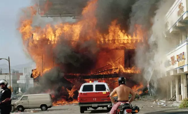 FILE - A Korean shopping mall burns in Los Angeles, April 30, 1992 on the second day of rioting in the city following the acquittal of four police officers for the 1991 beating of motorist Rodney King. (AP Photo/Nick Ut, file)