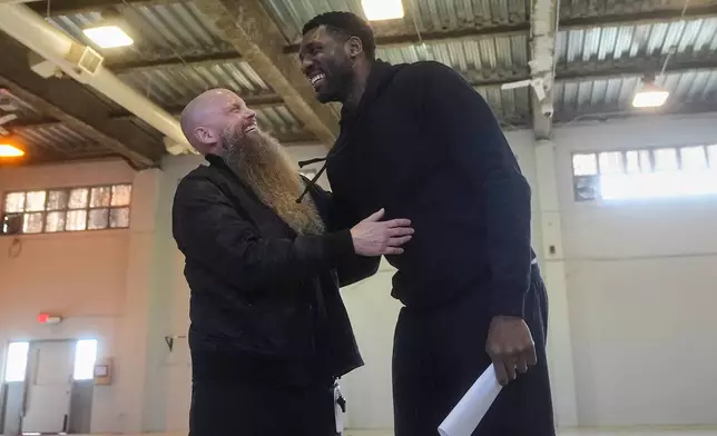Mental skills coach Graham Betchart, left, laughs with former NBA basketball player Festus Ezeli before Twinning Project cohort 2 participants graduated during the project's collaboration with the Golden State Warriors and the California Department of Corrections and Rehabilitation at Solano State Prison in Vacaville, Calif., Tuesday, Feb. 11, 2025. (AP Photo/Jeff Chiu)