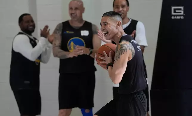 Viet Kim Le, foreground, smiles after making a basket as he and other Twinning Project cohort 2 perform basketball drills during the project's collaboration with the NBA's Golden State Warriors and the California Department of Corrections and Rehabilitation at Solano State Prison in Vacaville, Calif., Tuesday, Feb. 11, 2025. (AP Photo/Jeff Chiu)