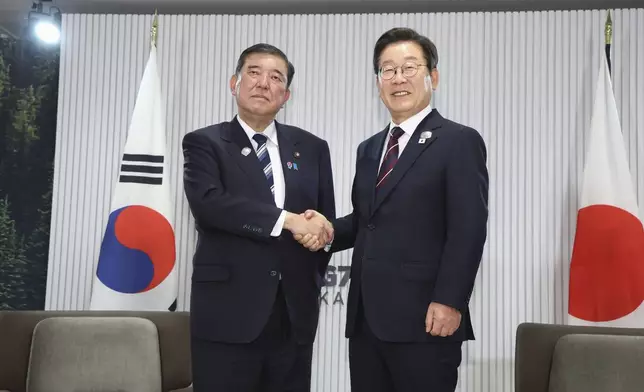 Japanese Prime Minister Shigeru Ishiba, left, and South Korean President Lee Jae Myung, right, shake hands ahead of a bilateral meeting on the sidelines of the G7, in Kananaskis, Alberta, on June 17, 2025. (Kyodo News via AP)