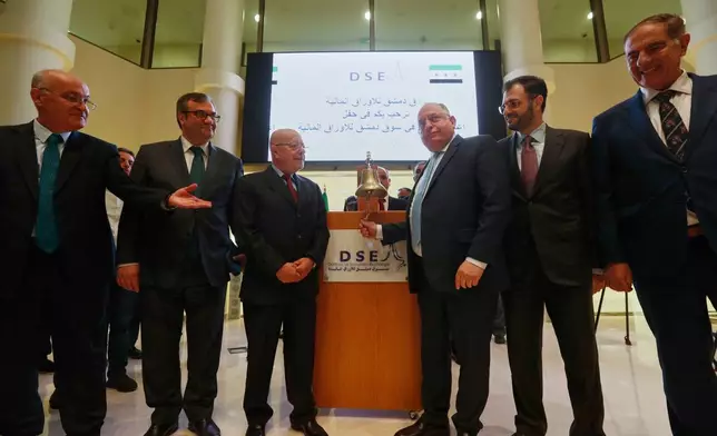 Syrian Finance Minister Mohammed Yisr Barnieh, center right, rings the opening bell at the Damascus Securities Exchange in Damascus, Syria, Monday, June 2, 2025. (AP Photo/Omar Sanadiki)