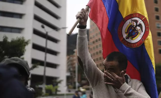 A man holds a Colombian flag as he marches to the clinic where Senator Miguel Uribe Turbay is being treated after an assassination attempt, in Bogota, Colombia, Sunday, June 8, 2025. (AP Photo/Ivan Valencia)