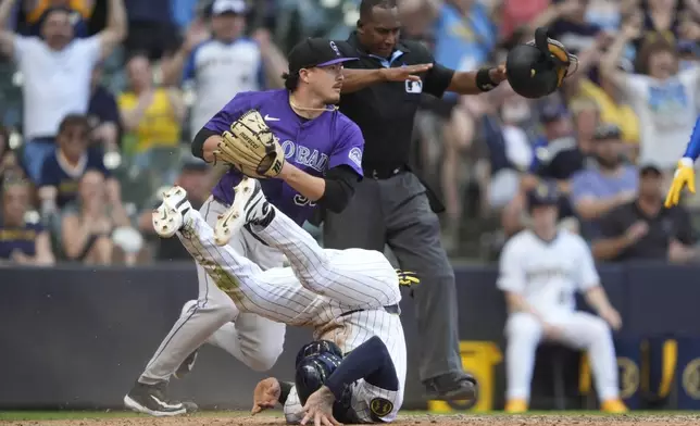 Milwaukee Brewers' Joey Ortiz, bottom, rolls after scoring on a wild pitch during the 10th inning of a baseball game against the Colorado Rockies, Sunday, June 29, 2025, in Milwaukee. (AP Photo/Aaron Gash)