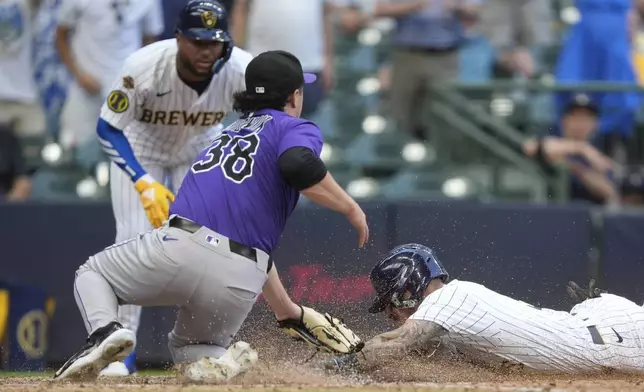 Milwaukee Brewers' Joey Ortiz, right, scores on a wild pitch past the tag of Colorado Rockies' Victor Vodnik during the 10th inning of a baseball game, Sunday, June 29, 2025, in Milwaukee. (AP Photo/Aaron Gash)