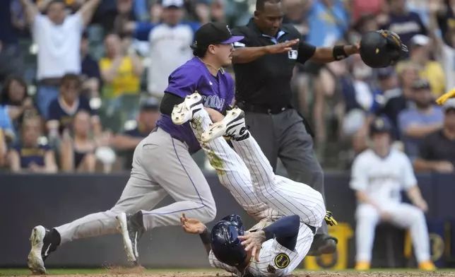 Milwaukee Brewers' Joey Ortiz, bottom, rolls after scoring on a wild pitch during the 10th inning of a baseball game against the Colorado Rockies, Sunday, June 29, 2025, in Milwaukee. (AP Photo/Aaron Gash)