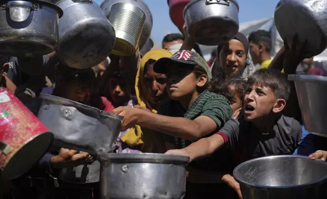 Palestinians struggle to get donated food at a community kitchen in Khan Younis, southern Gaza Strip, Monday, June 2, 2025. (AP Photo/Abdel Kareem Hana)