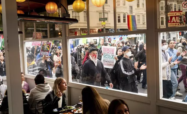 EDS NOTE: OBSCENITY - Protesters against U.S. Immigration &amp; Customs Enforcement raids pass diners while marching through San Francisco's Mission district on Monday, June 9, 2025. (AP Photo/Noah Berger)