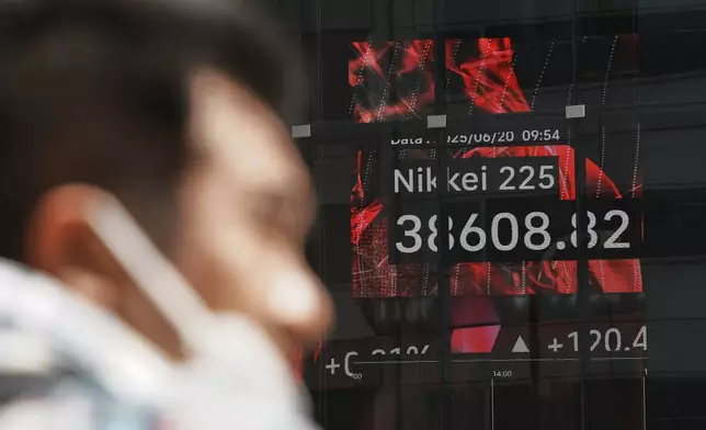 A person stands in front of an electronic stock board showing Japan's Nikkei index at a securities firm Friday, June 20, 2025, in Tokyo. (AP Photo/Eugene Hoshiko)