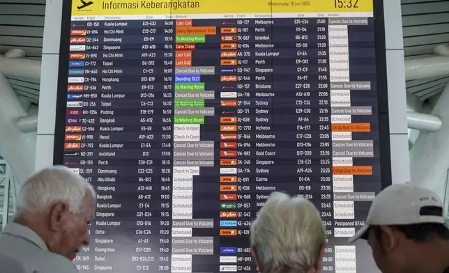 Passengers check an information board showing disrupted flight schedule due to the eruption of Mount Lewotobi Laki-Laki, at Ngurah Rai International Airport in Badung, Bali, Indonesia, Wednesday, June 18, 2025. (AP Photo/Herdyanto)