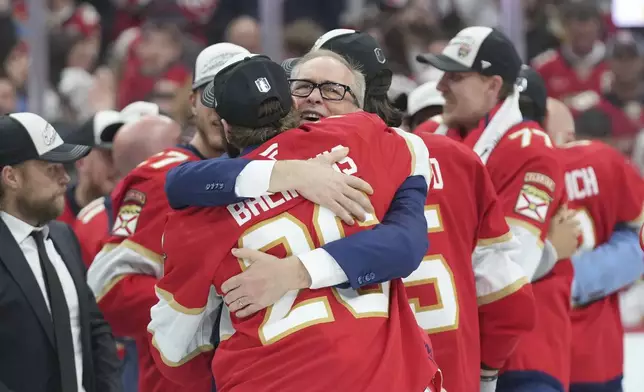 Florida Panthers head coach Paul Maurice hugs defenseman Uvis Balinskis (26) after defeating the Edmonton Oilers in Game 6 of the NHL hockey Stanley Cup Final Tuesday, June 17, 2025, in Sunrise, Fla. (AP Photo/Lynne Sladky)