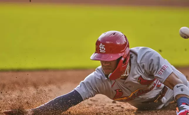 St. Louis Cardinals' Masyn Winn dives back into first base as the ball gets away from Cleveland Guardians first baseman Kyle Manzardo on a pickoff-attempt in the third inning of a baseball game in Cleveland, Friday, June 27, 2025. (AP Photo/Sue Ogrocki)